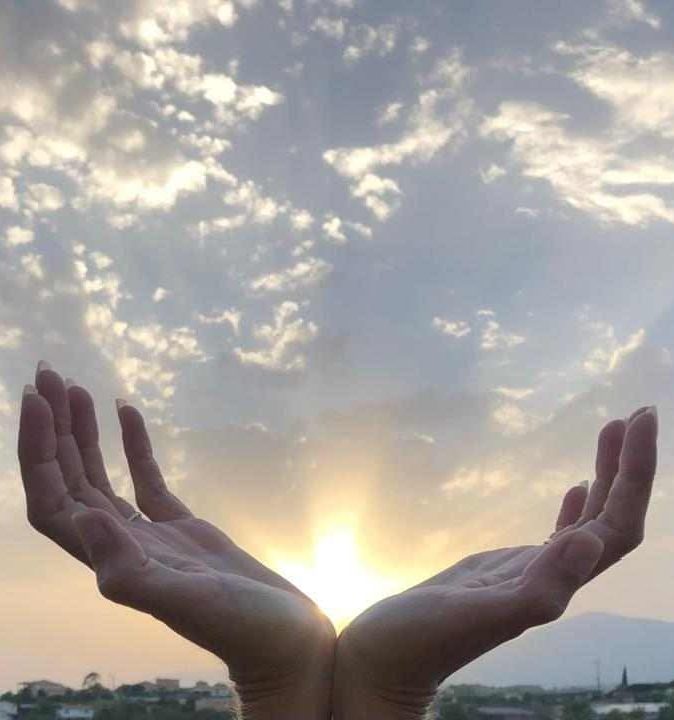 Deux mains ouvertes vers le ciel au lever du soleil, illustrant l’énergie du magnétisme et l’harmonie entre le corps et l’esprit.